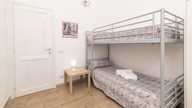 A bunk bed room with a wooden table, a lamp, and a painting on the wall. - Dimora Oleandro 50m From Beach (Stintino)
