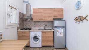 A compact kitchen with wooden cabinets, a washing machine, a refrigerator, and a sink. - Dimora Oleandro 50m From Beach (Stintino)