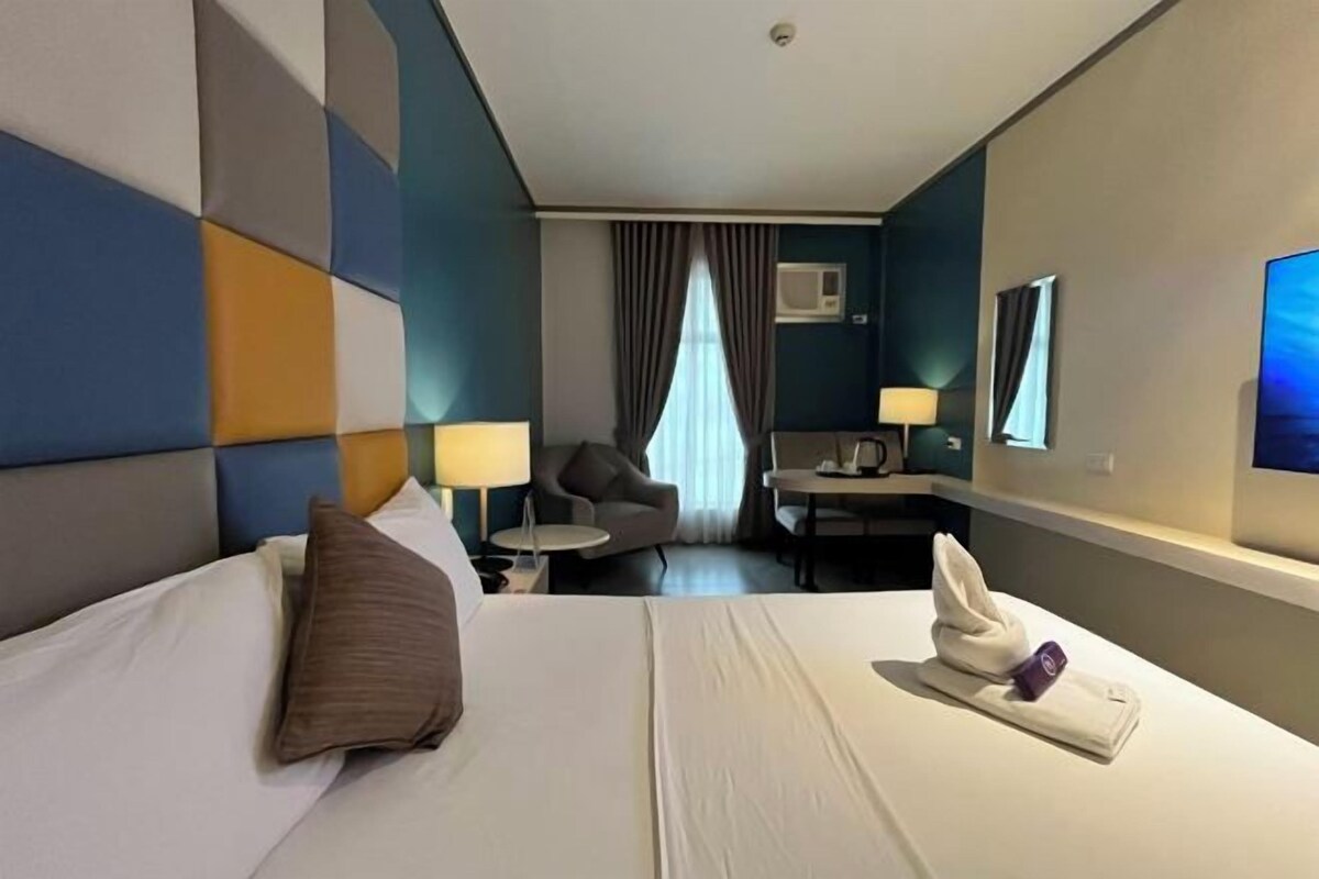 Una habitación de hotel con cama, escritorio, silla y televisión.