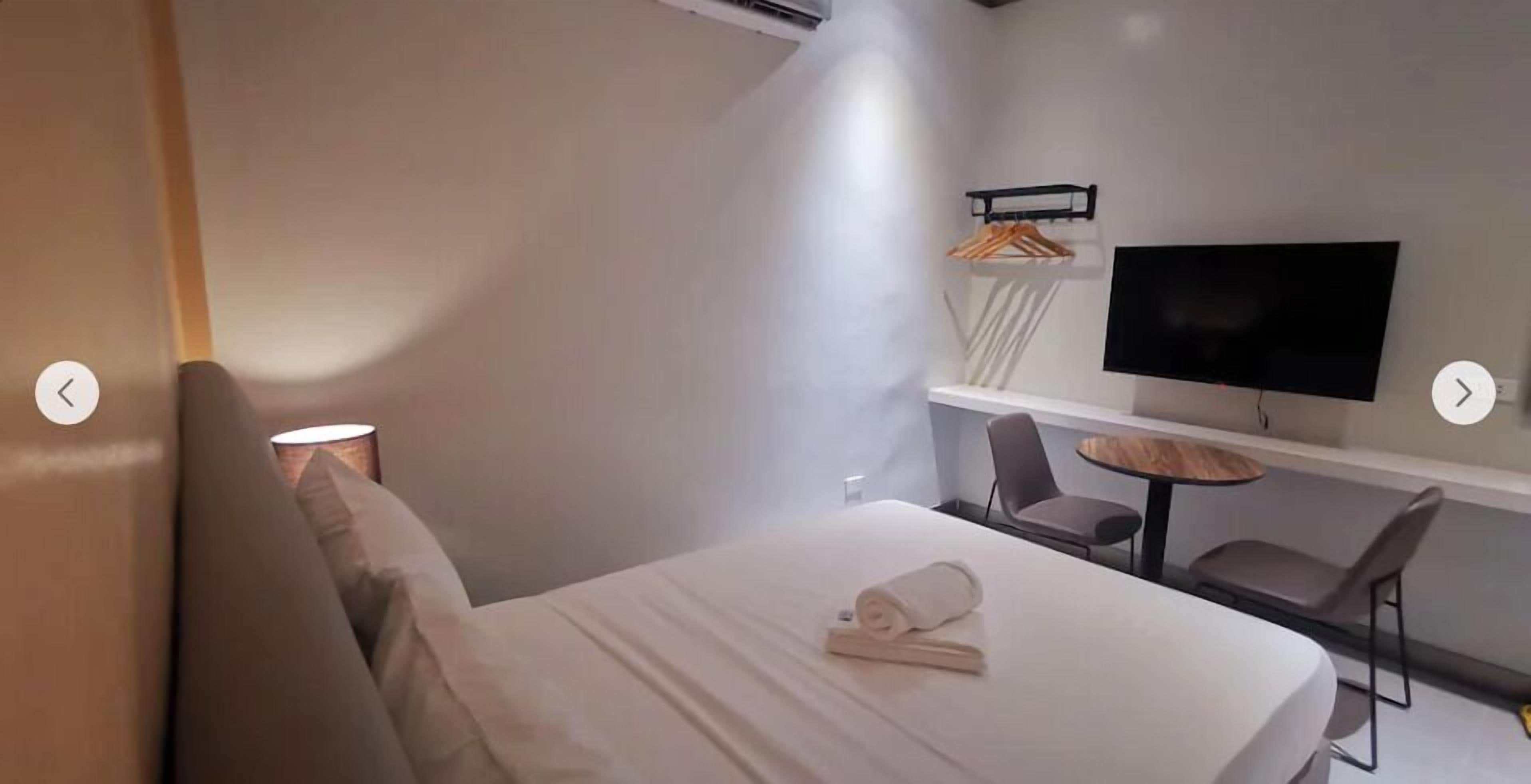 Quarto de hotel moderno com cama, televisão, escrivaninha e cadeira.