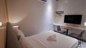 Quarto de hotel moderno com cama, televisão, escrivaninha e cadeira.