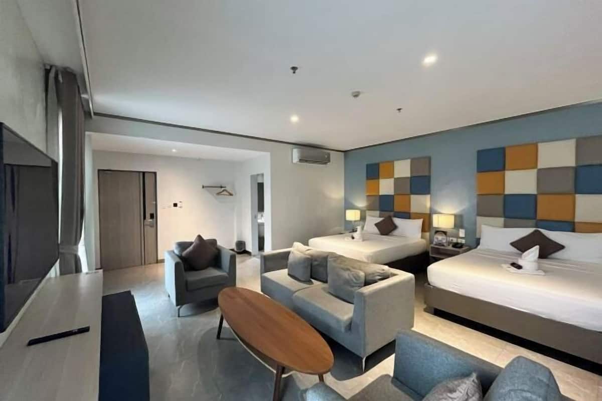 A modern hotel room with a sofa, two beds, a TV, and a wall with a geometric pattern.