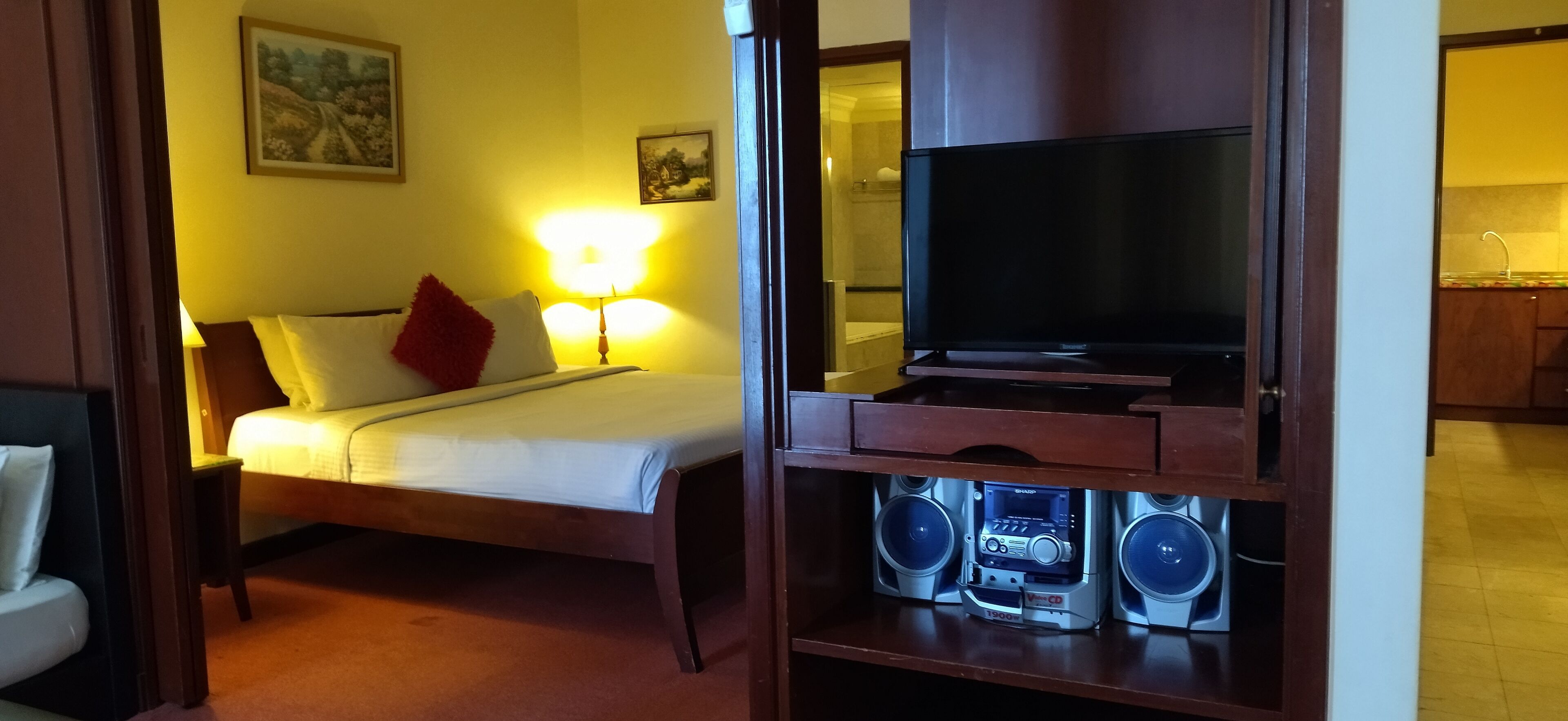 Une chambre d’hôtel équipée d’un lit, de lampes de chevet, d’un téléviseur et d’un système audio intégré.