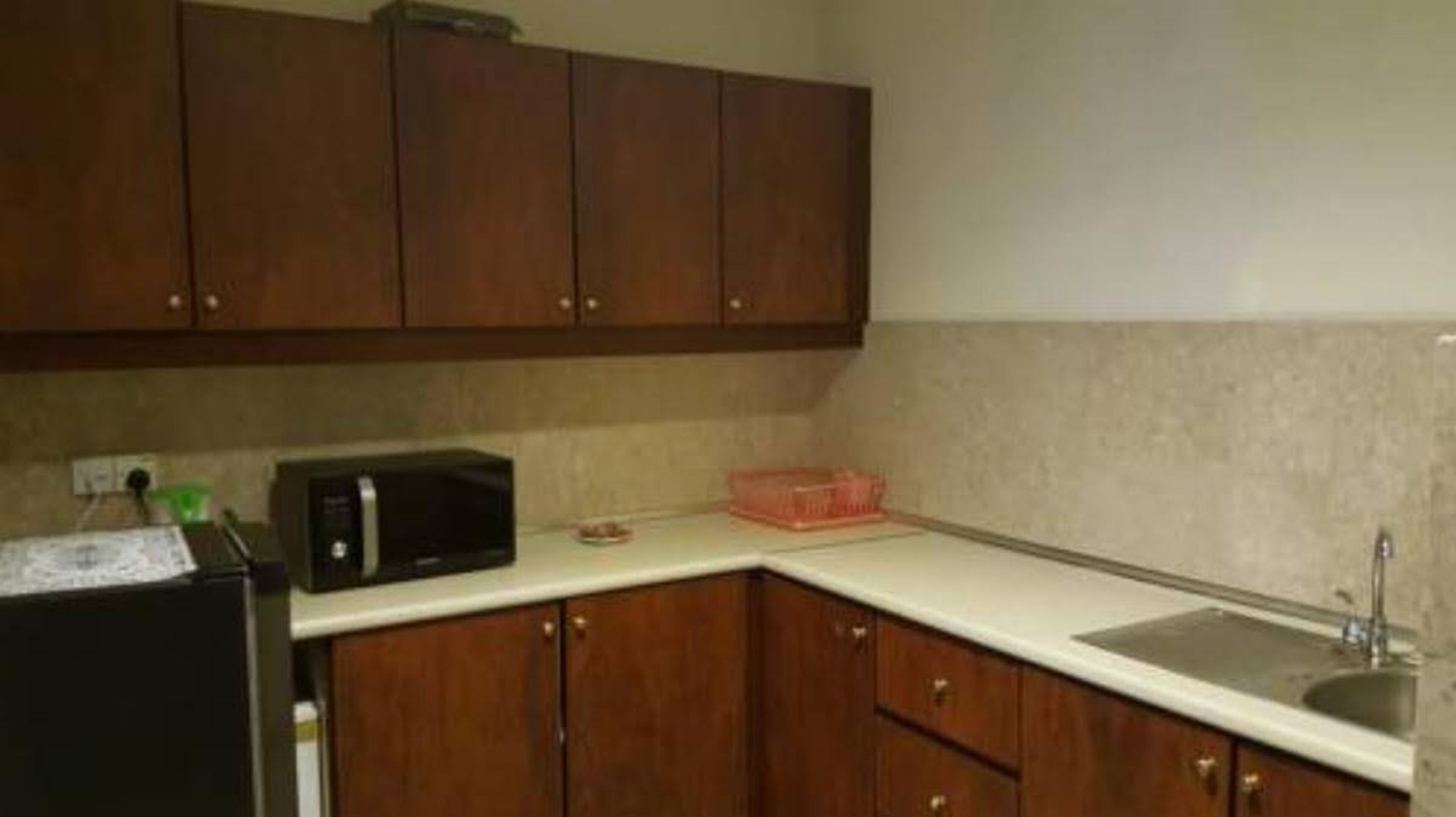 A small kitchen with wooden cabinets, a microwave, a sink, and a countertop.