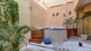 Ein Innenhof mit Whirlpool, Sitzgelegenheit und Kübelpflanzen.