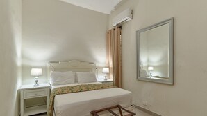 Ein Schlafzimmer mit Bett, Nachttischen, einem Spiegel und einer Klimaanlage.