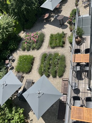 An outdoor patio with multiple tables and chairs, surrounded by potted plants and flowers. - Aparthotel Parsberg Green Design Ferstl (Parsberg)