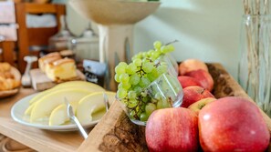 A wooden table with sliced apples, a bowl of green grapes, and whole red apples. - Aparthotel Parsberg Green Design Ferstl (Parsberg)