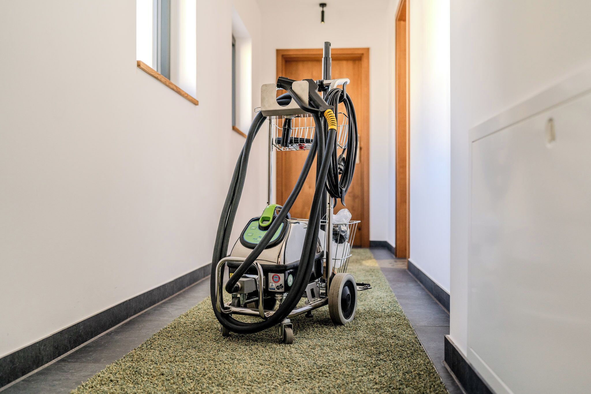 A hallway with a carpeted floor and a cleaning machine.