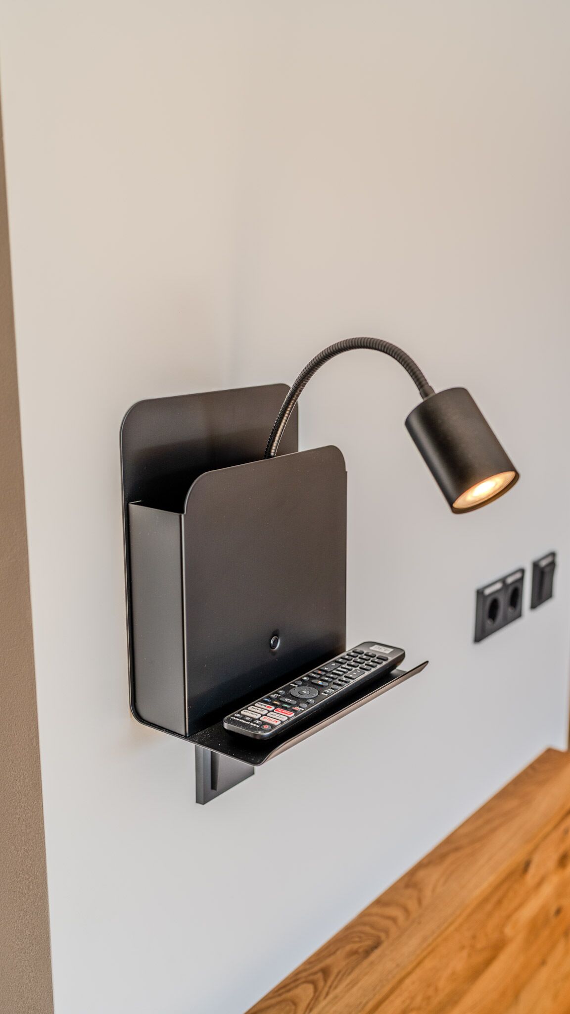 Un faretto a parete con ripiano per telecomando.