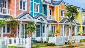 Una hilera de casas coloridas con vallas blancas y un cielo azul despejado.