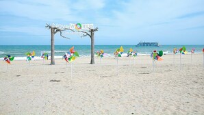 Una playa con giravientos de colores y un letrero que dice "Nova World Photography".