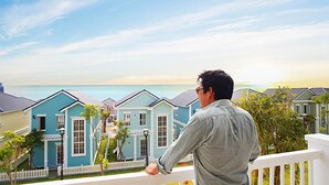Un hombre contempla una hilera de casas de colores pastel con vista al océano.