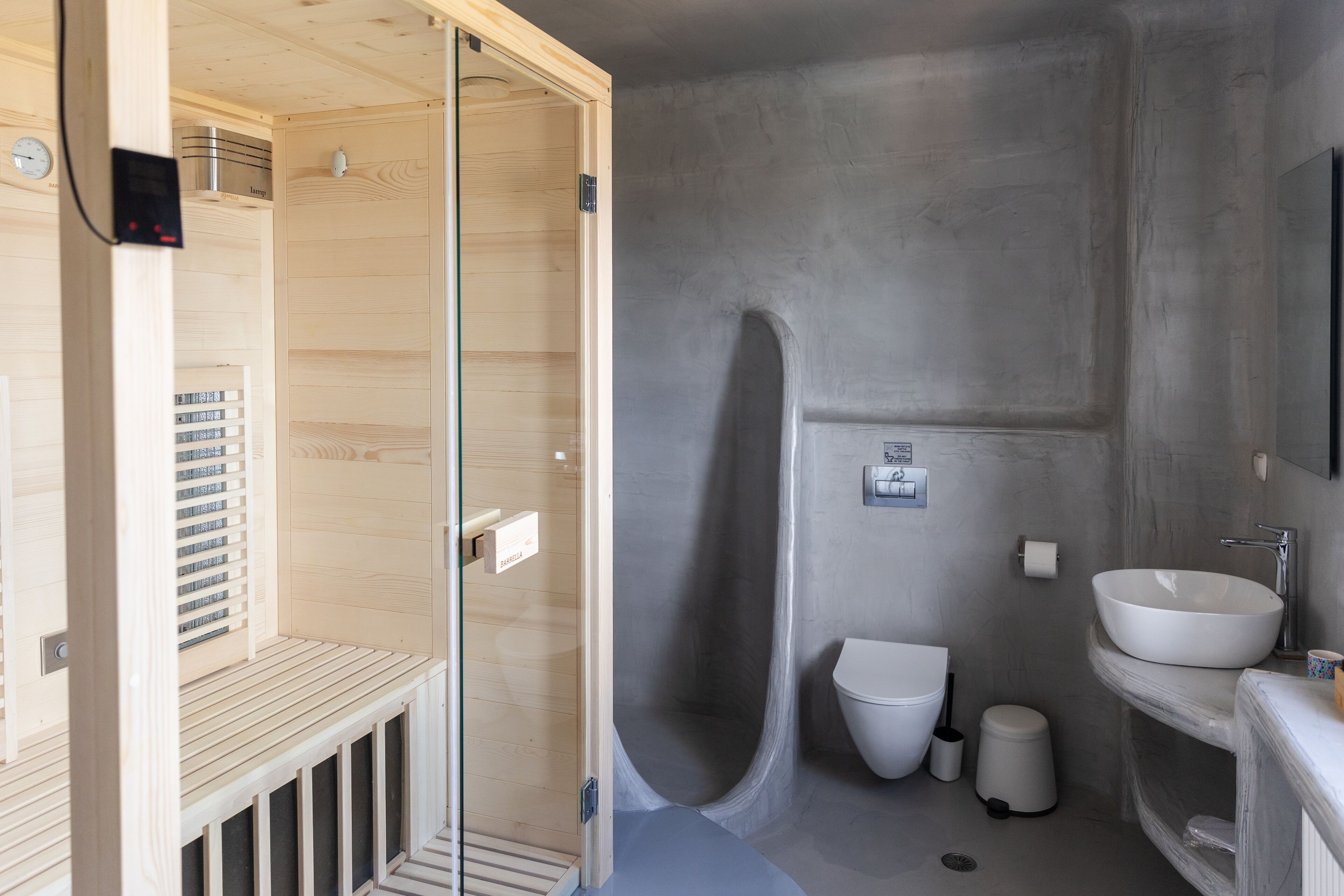 A modern bathroom with a wooden shower enclosure, a built-in sink, and a toilet.
