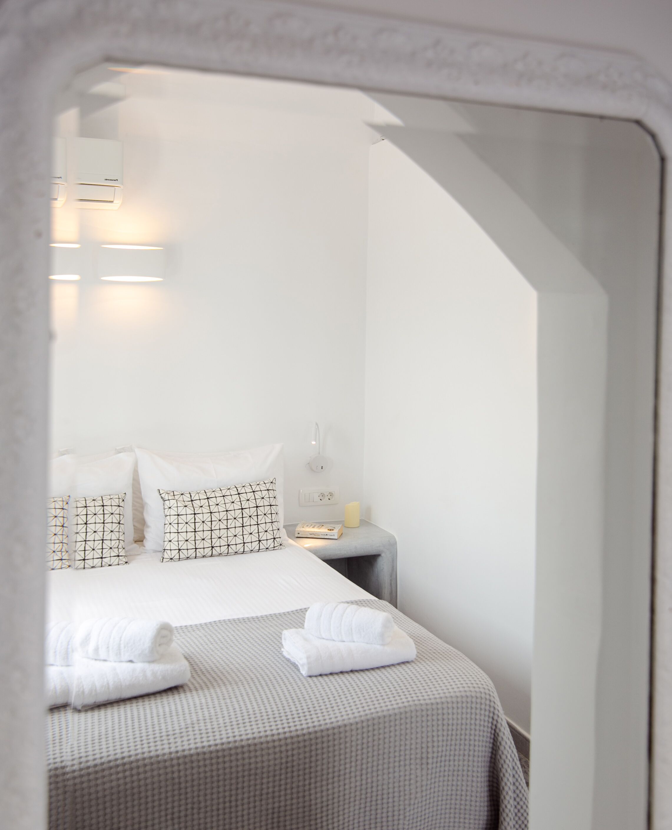 A neatly made bed with patterned pillows and a bedside table with a lamp and a book.