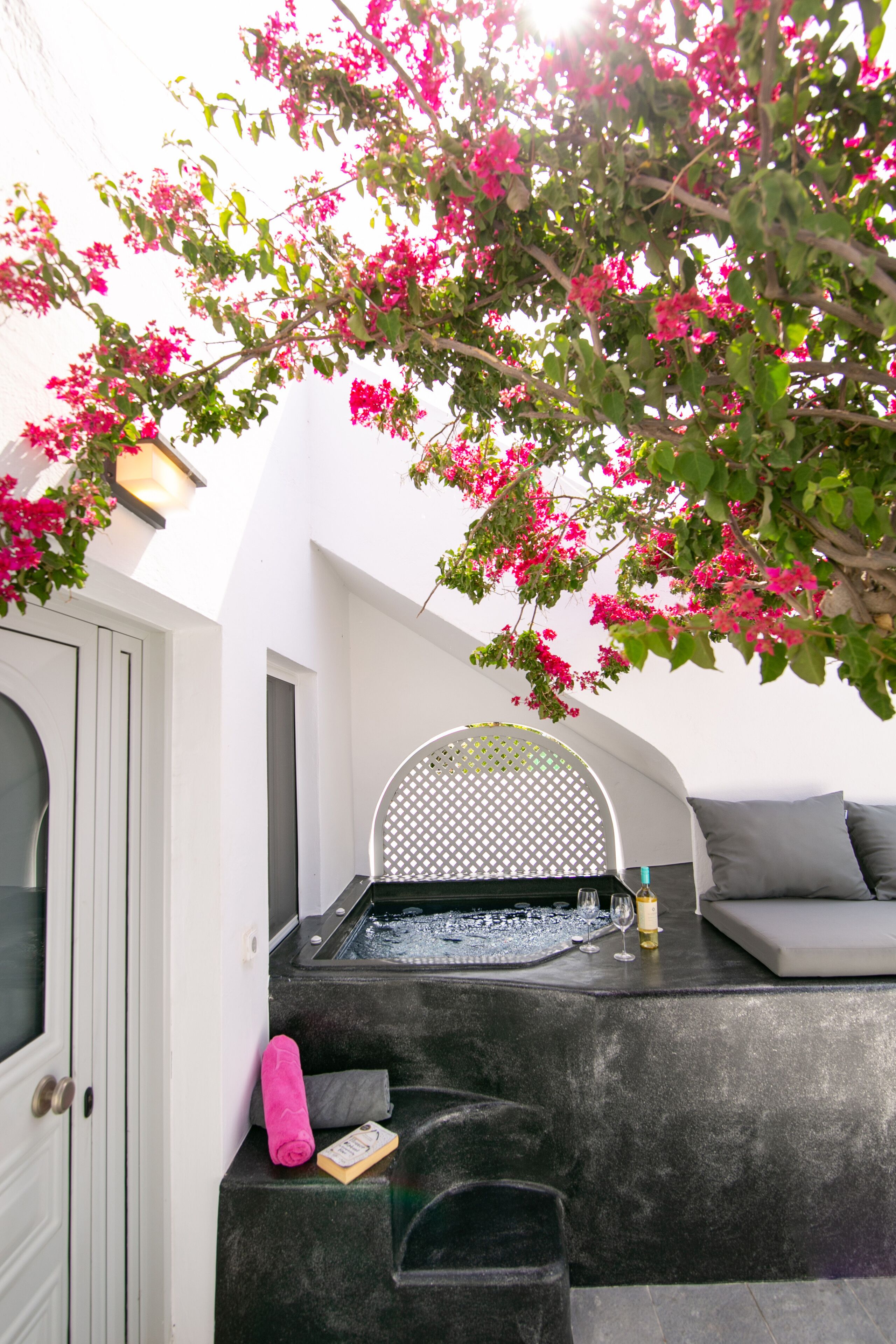 A spa area with a black stone bench, a white chair, and a small table with a glass.
