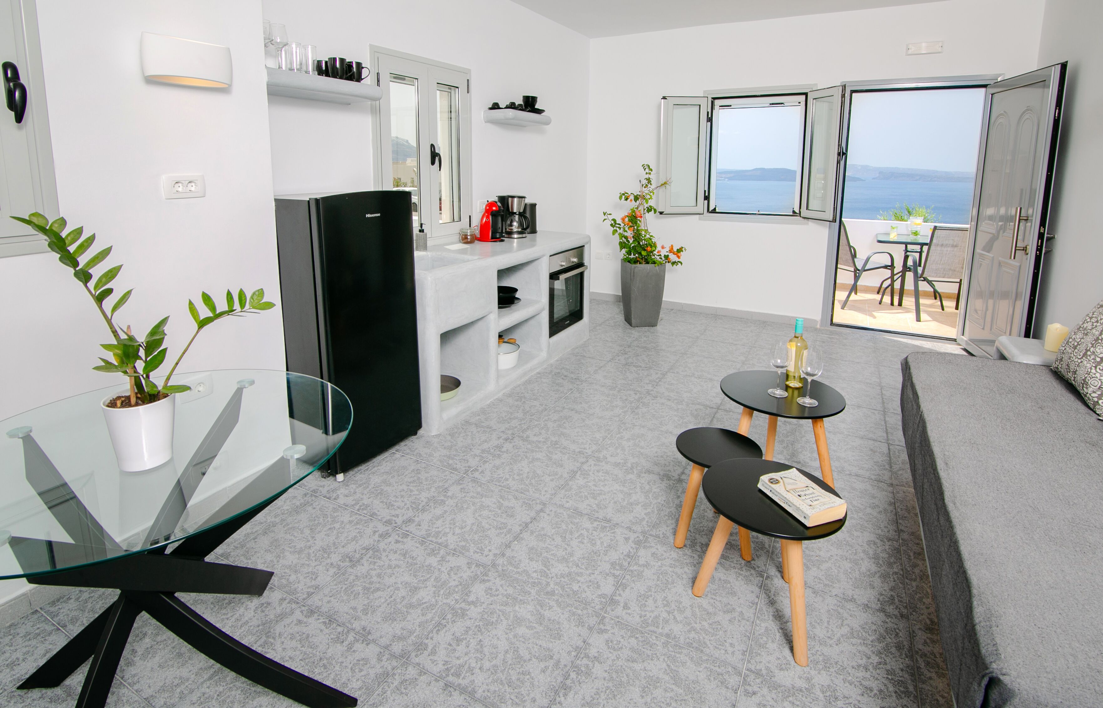 Una cocina moderna con refrigerador, estufa y comedor con mesa de vidrio y sillas.