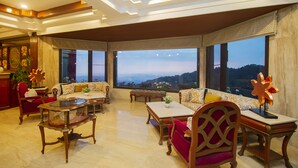 A spacious living room with a high ceiling, large windows, and a view of the landscape. - Amritara Surya – A Luxury Spa Retreat (Dharamshala)