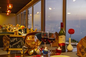 Een restauranttafel met een kaars, wijn glazen, een fles wijn en een bordje 'Gefeliciteerd met jullie verjaardag'.