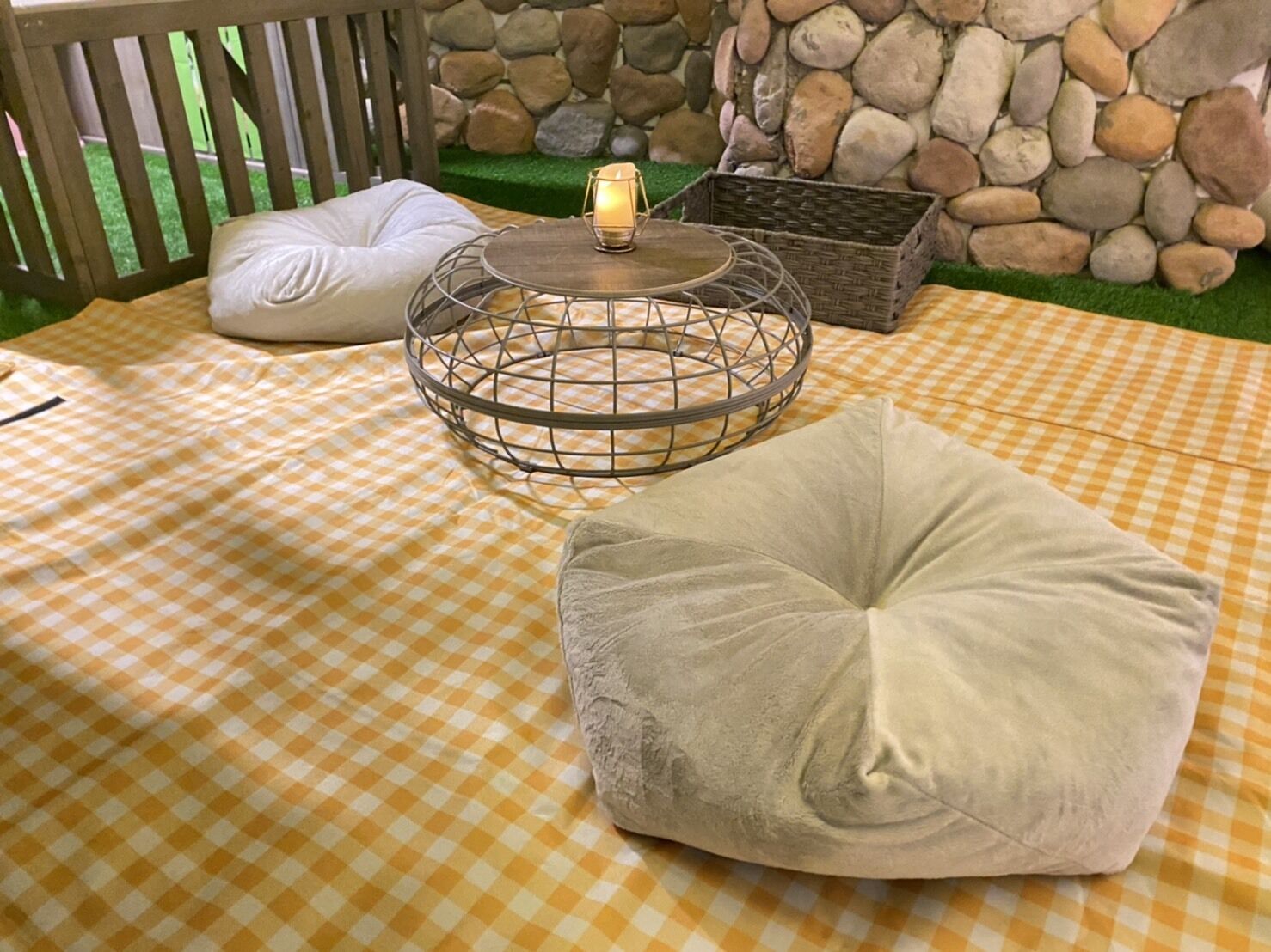 A checkered outdoor seating area with a round metal table and a cushion.