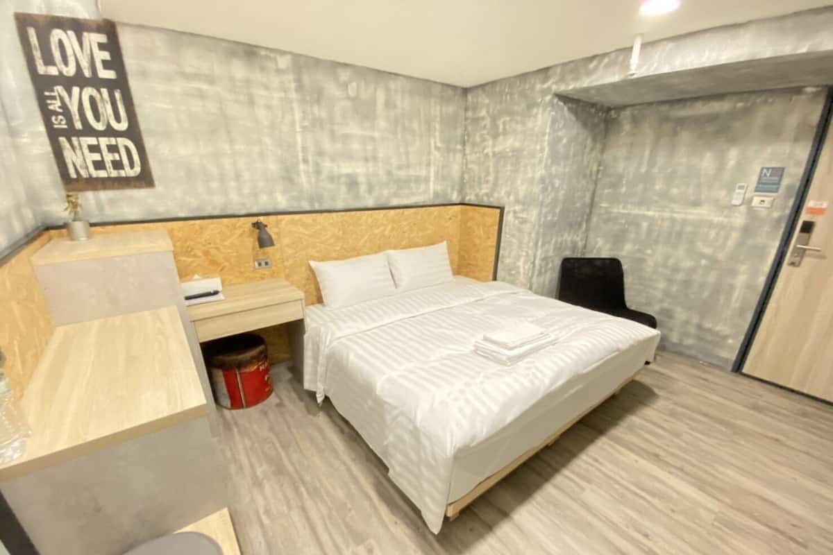 Ein Hotelzimmer mit einem Bett, einem Schreibtisch, einem Stuhl und einem an der Wand befestigten Schild.