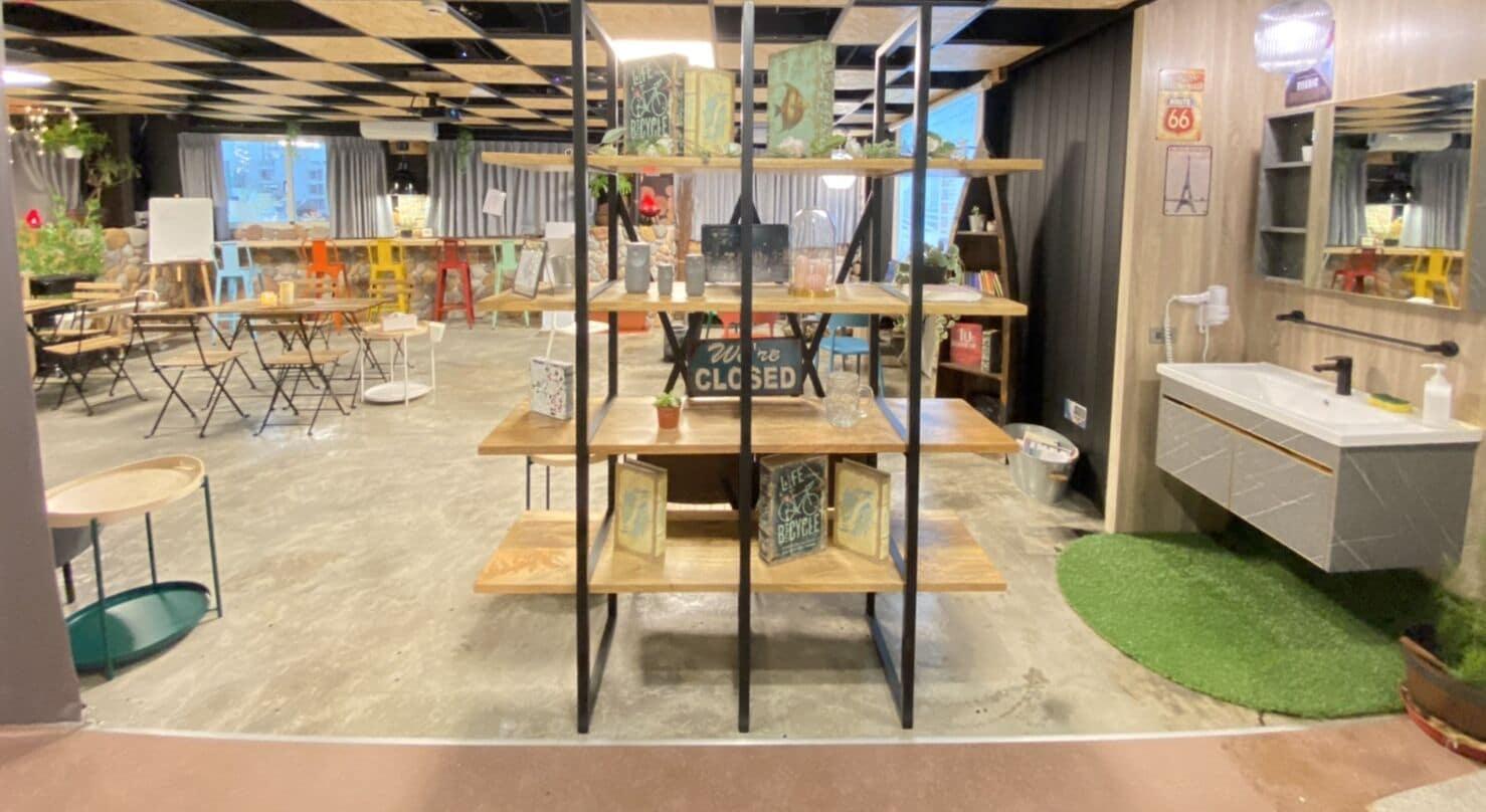 Un café con techo a cuadros, un letrero de cerrado en una estantería y un baño con espejo y lavabo.