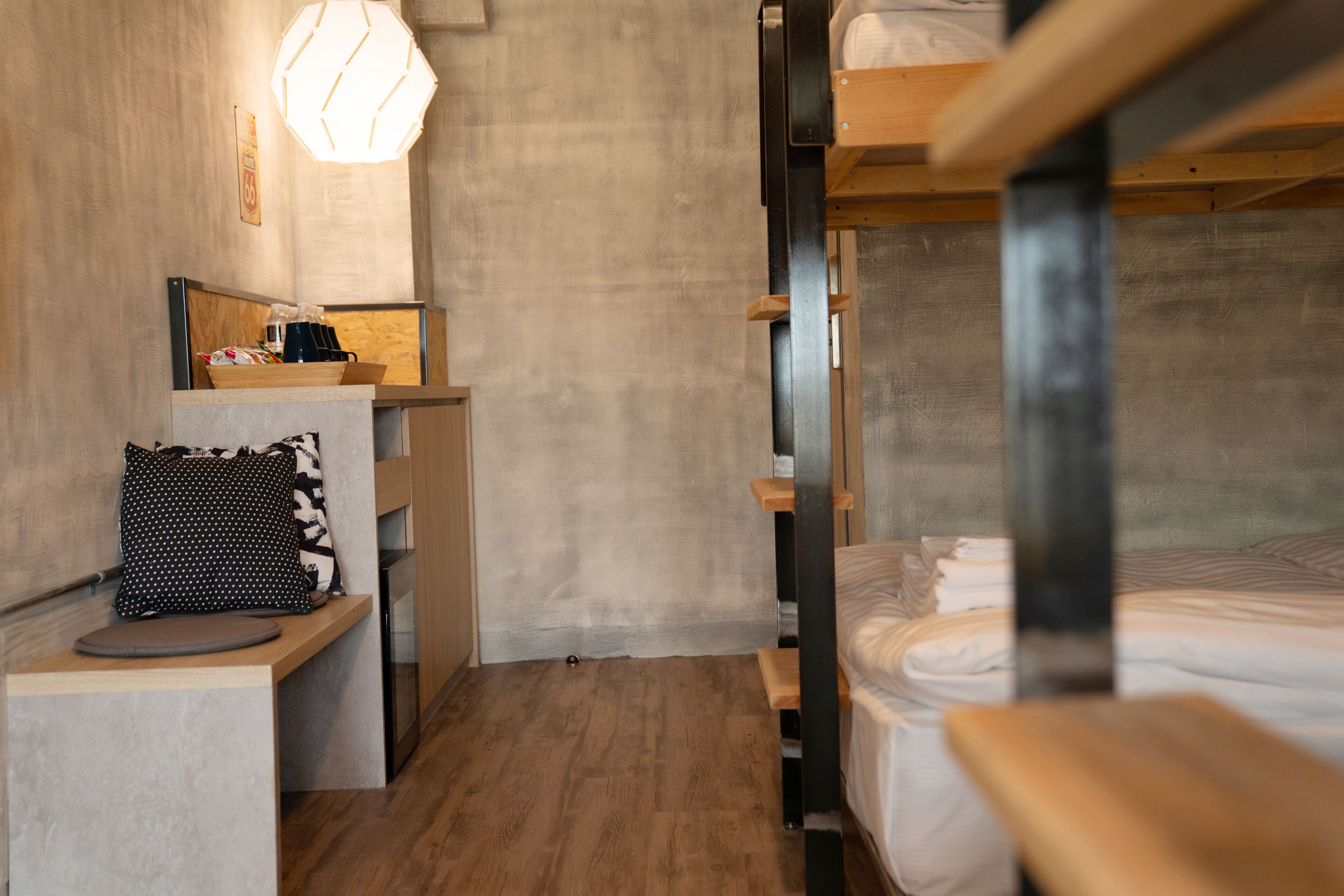 Une chambre compacte et moderne, dotée de lits superposés, d’un petit bureau et d’un plancher en bois.