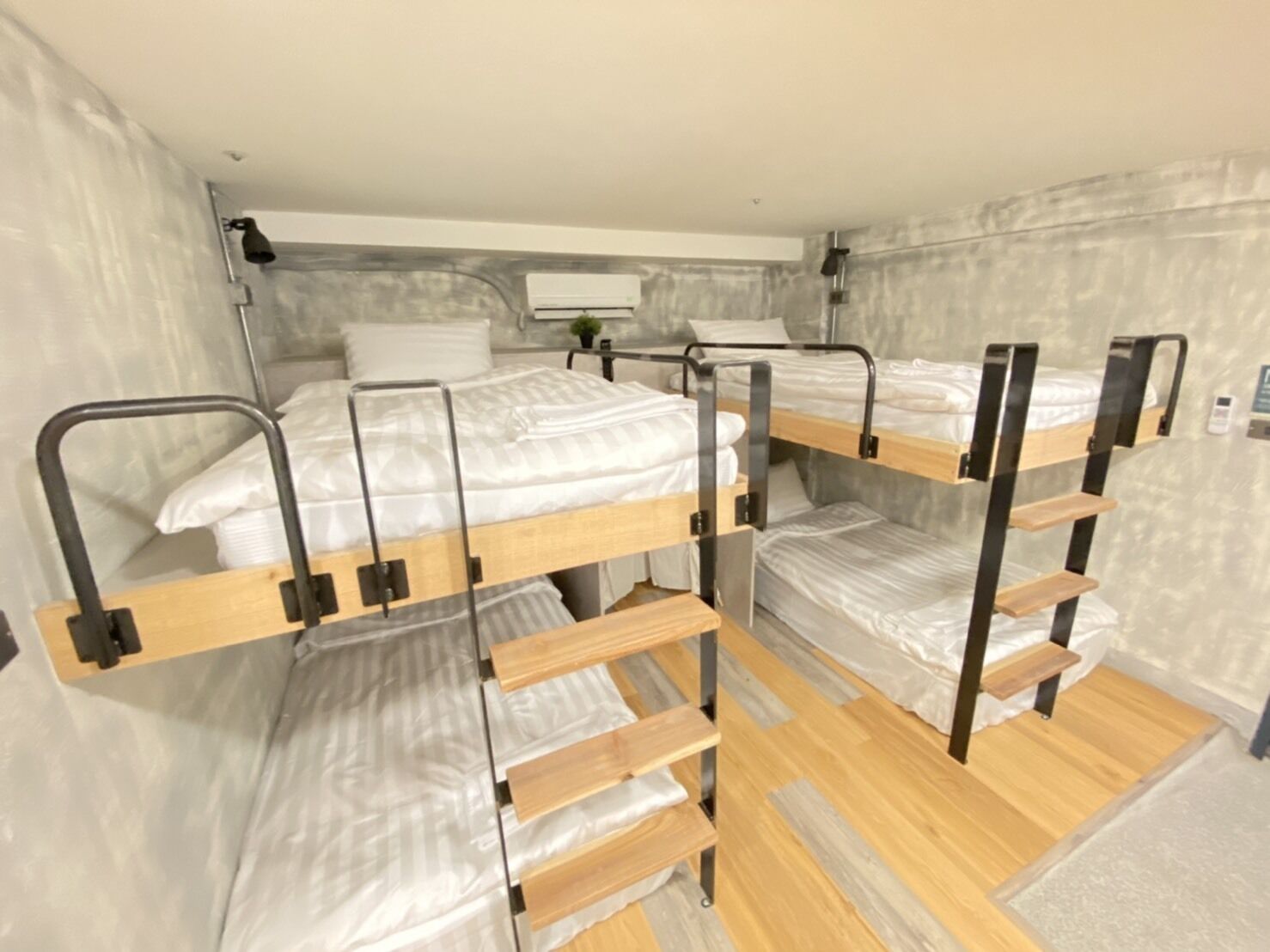 Habitación con literas de madera, una mesita de noche y una lámpara fijada a la pared.
