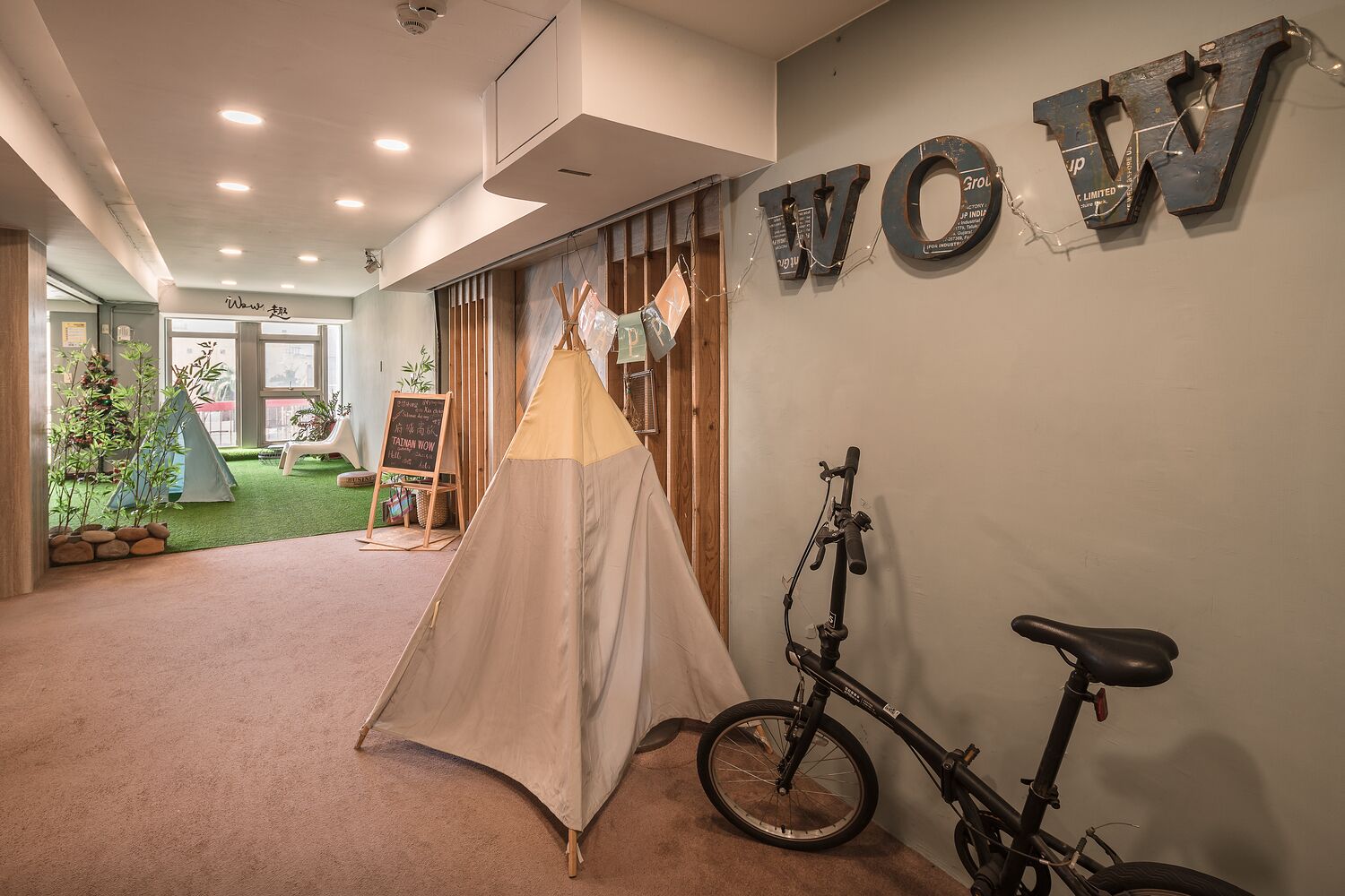 Una habitación con una tienda de campaña, una bicicleta y la palabra 'WOW' en la pared.