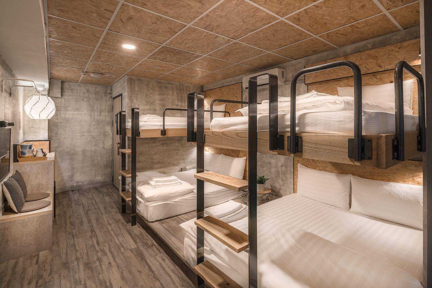 A bunk bed room with wooden floors and a tiled ceiling.