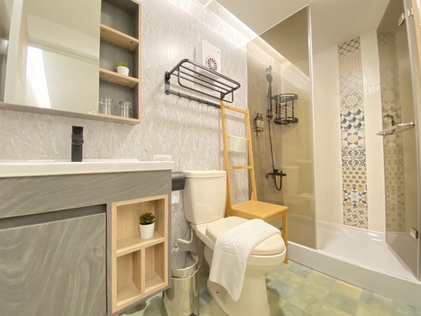 A modern bathroom with a toilet, a shower, and a vanity with shelves.