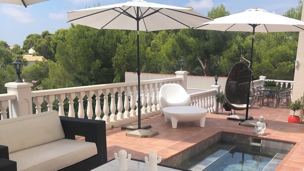 Eine Dachterrasse mit Gartenmöbeln, einem Pool und Sonnenschirmen.