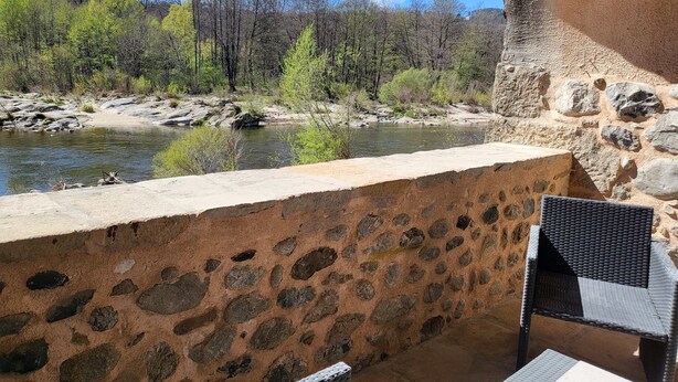 A stone wall overlooking a river with trees and a distant church. - Bel Appartement en sud Ardèche au Bord de la Rivière (Ucel)