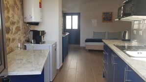 A compact kitchen with a sink, stove, and a small dining area with a bench. - House in the historic center  (BELMONTE)