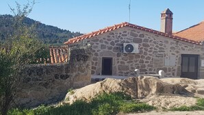 A stone building with a tiled roof, a chimney, and a door labeled "Isabel de Gouveia". - House in the historic center  (BELMONTE)
