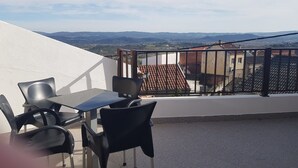 A terrace with a table and chairs, a white wall, and a view of distant hills. - House in the historic center  (BELMONTE)
