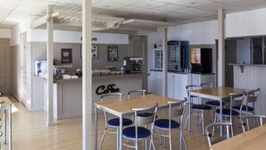 A modern kitchen with a coffee station, wooden tables, and blue chairs.