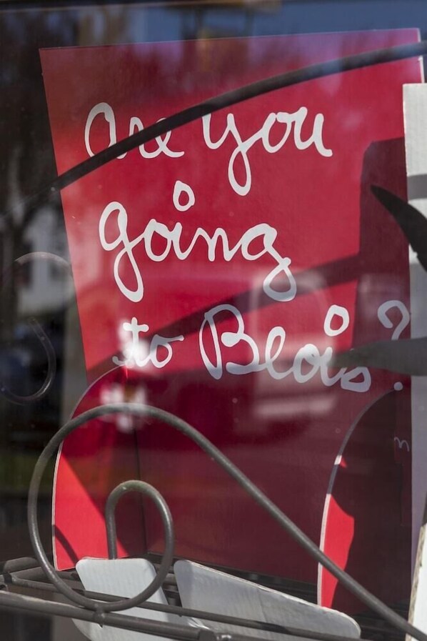 A red sign with white cursive text on a window.