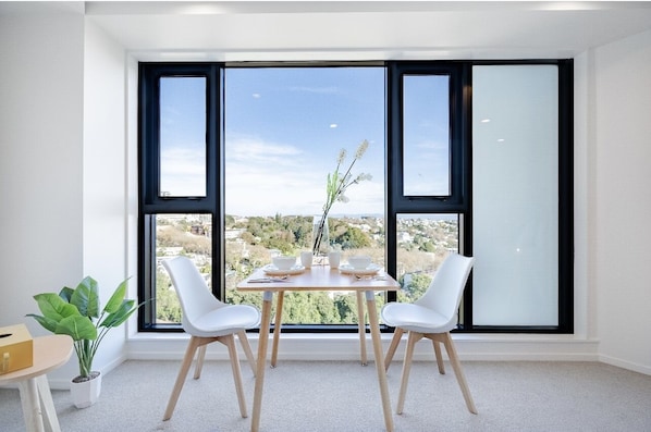 Enjoy a serene view of the surrounding landscape from this stylish room, featuring a table for two and a potted plant.