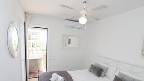 A hotel room with a bed, pillows, a ceiling fan, and a window.