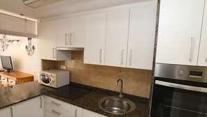 A modern kitchen with white cabinets, a granite countertop, a built-in microwave, a stainless steel sink, and a double oven.