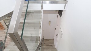 A modern interior with a glass staircase, white walls, and a patterned floor.