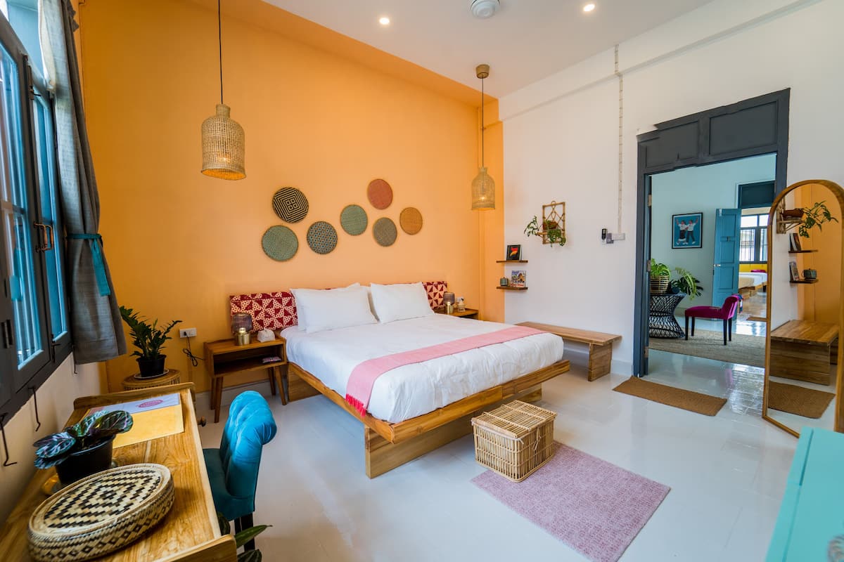 A modern bedroom with a large bed, bedside tables, a desk, and a chair.