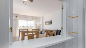 Une cuisine moderne avec un plan de travail blanc, des chaises en bois et un coin repas comprenant une table et des chaises.