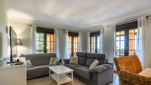 Ein modernes Wohnzimmer mit einem grauen Sofa, einem weißen Couchtisch und einem Korbstuhl.