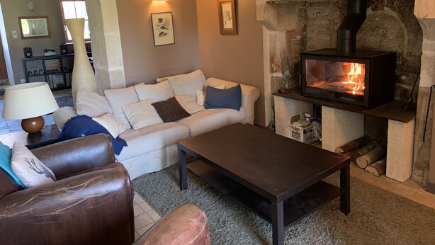 A cozy living room with a stone fireplace, a sofa, a coffee table, and a television.