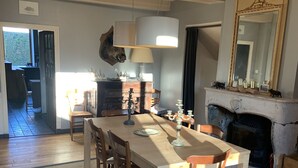 A dining area with a wooden table and chairs, a fireplace, and a mirror above it.