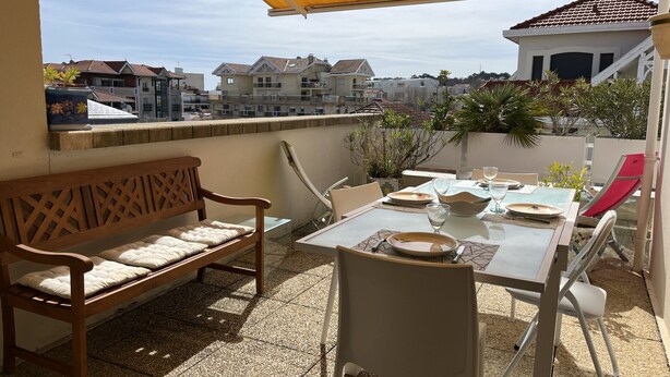 Una terraza con mesa lista para comer, un banco de madera y un dosel amarillo.