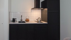 A modern kitchen with dark cabinets, a stainless steel kettle, and a coffee maker. - Rural B&B with a beautiful outdoor view and a village atmosphere! (Rhenen)