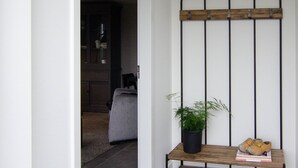 A hallway with a bench, a potted plant, and a pair of shoes on the bench. - Rural B&B with a beautiful outdoor view and a village atmosphere! (Rhenen)